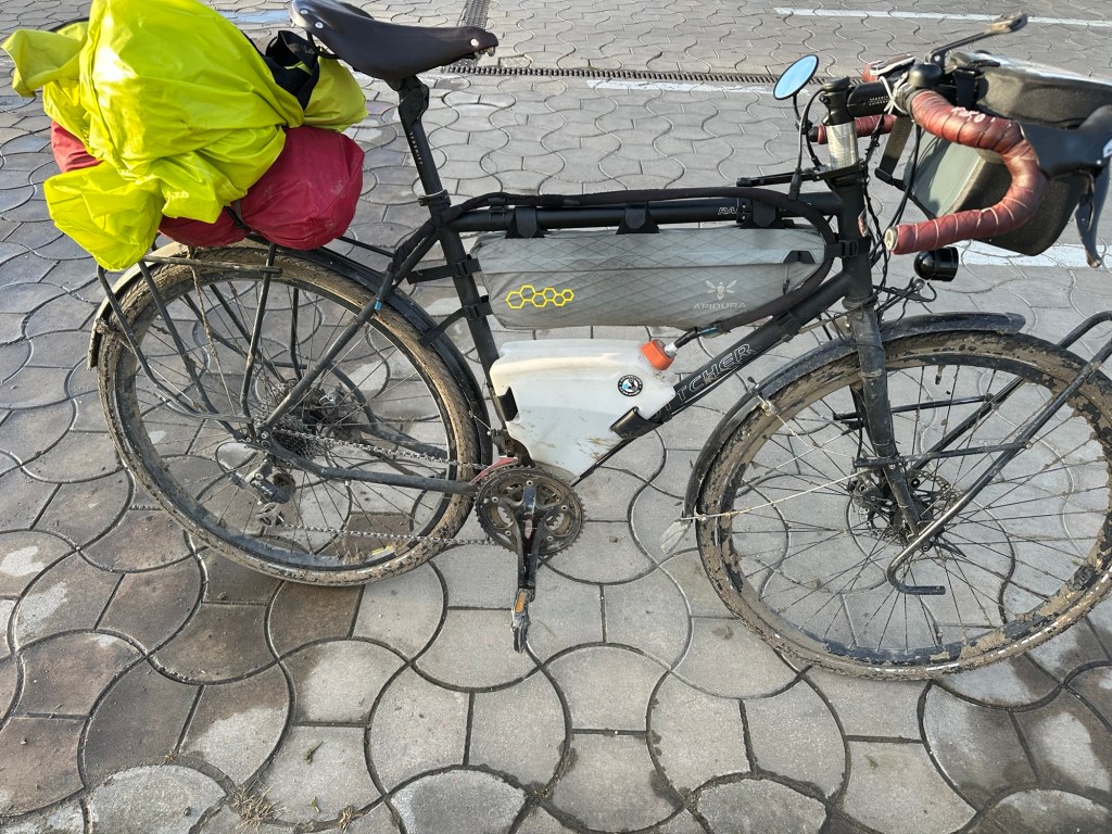 A bicycle loaded with colorful bags, resting on a patterned pavement.